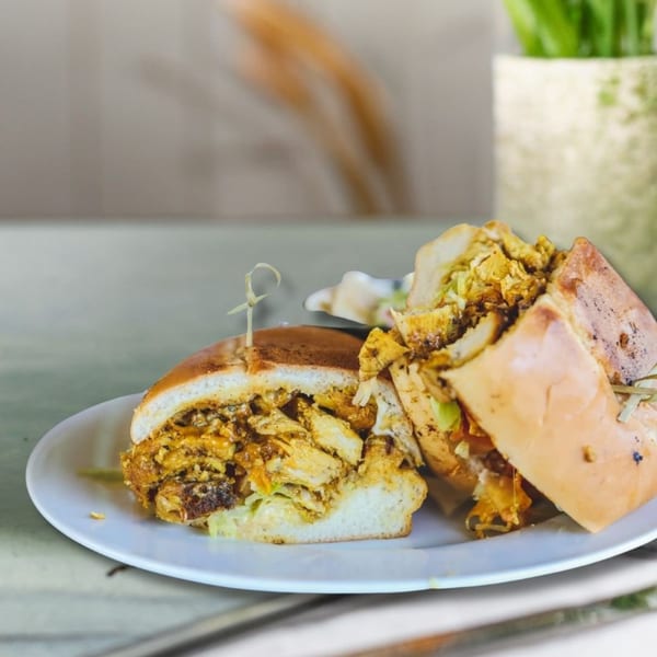 Two halves of a chicken sandwich with lettuce and sauce on a white plate.